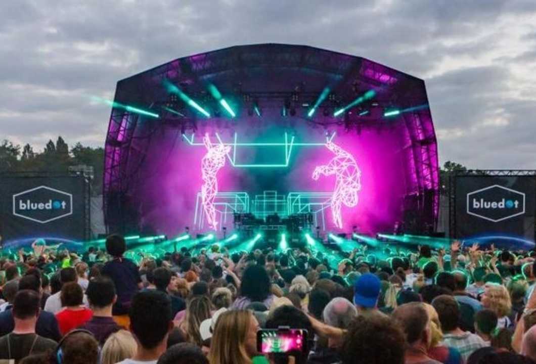 A large crowd in front of a stage at a festival.