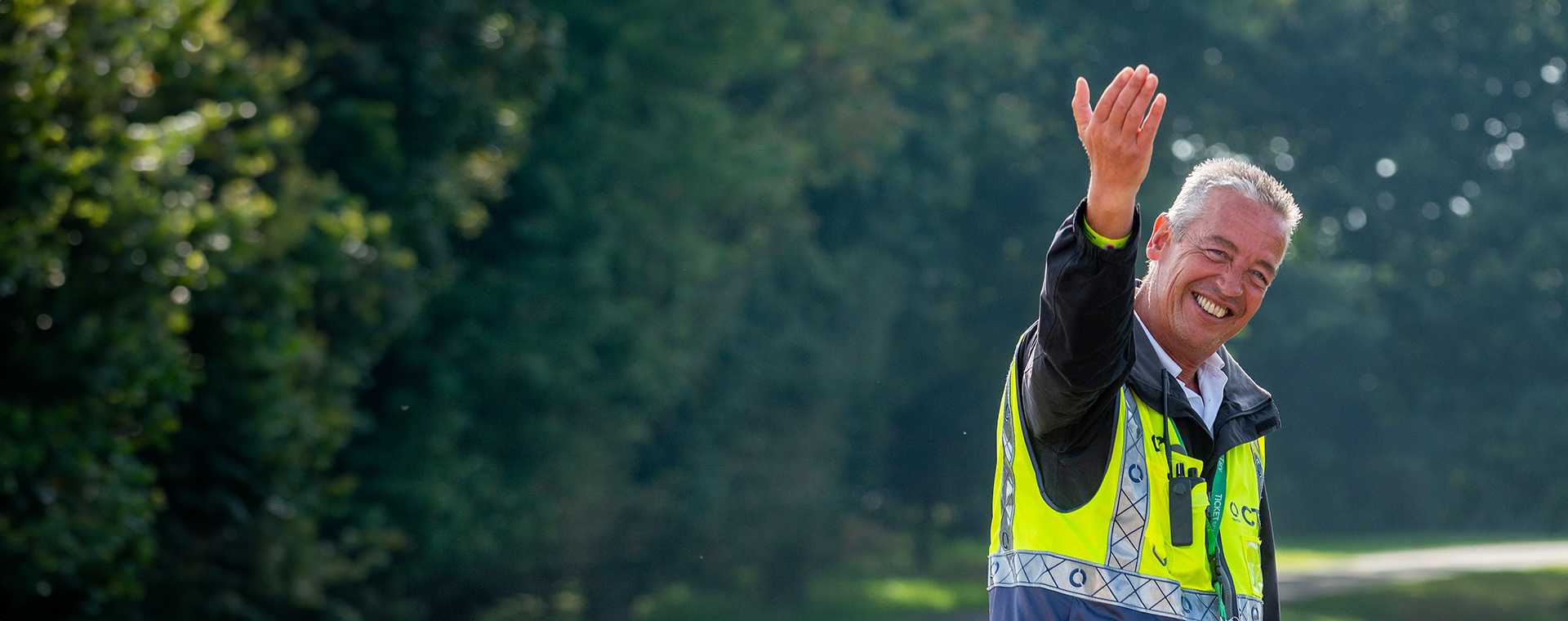 A Tracsis Events Marshal beckoning traffic and smiling