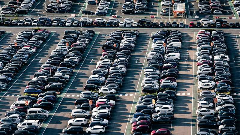 An aerial view of cars parked in rows in a car park