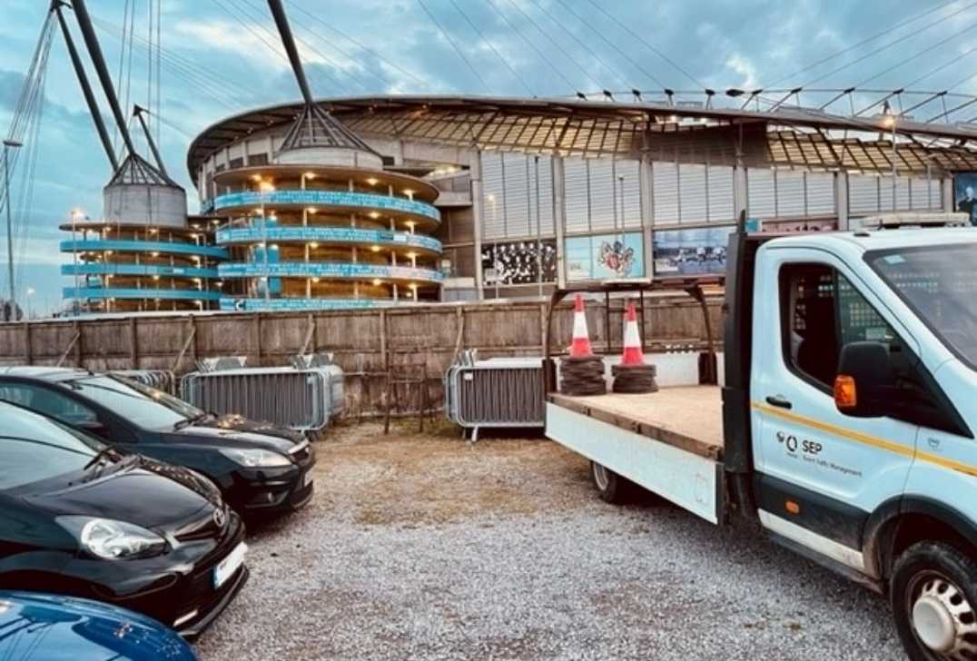 A car park with a stadium in the background.